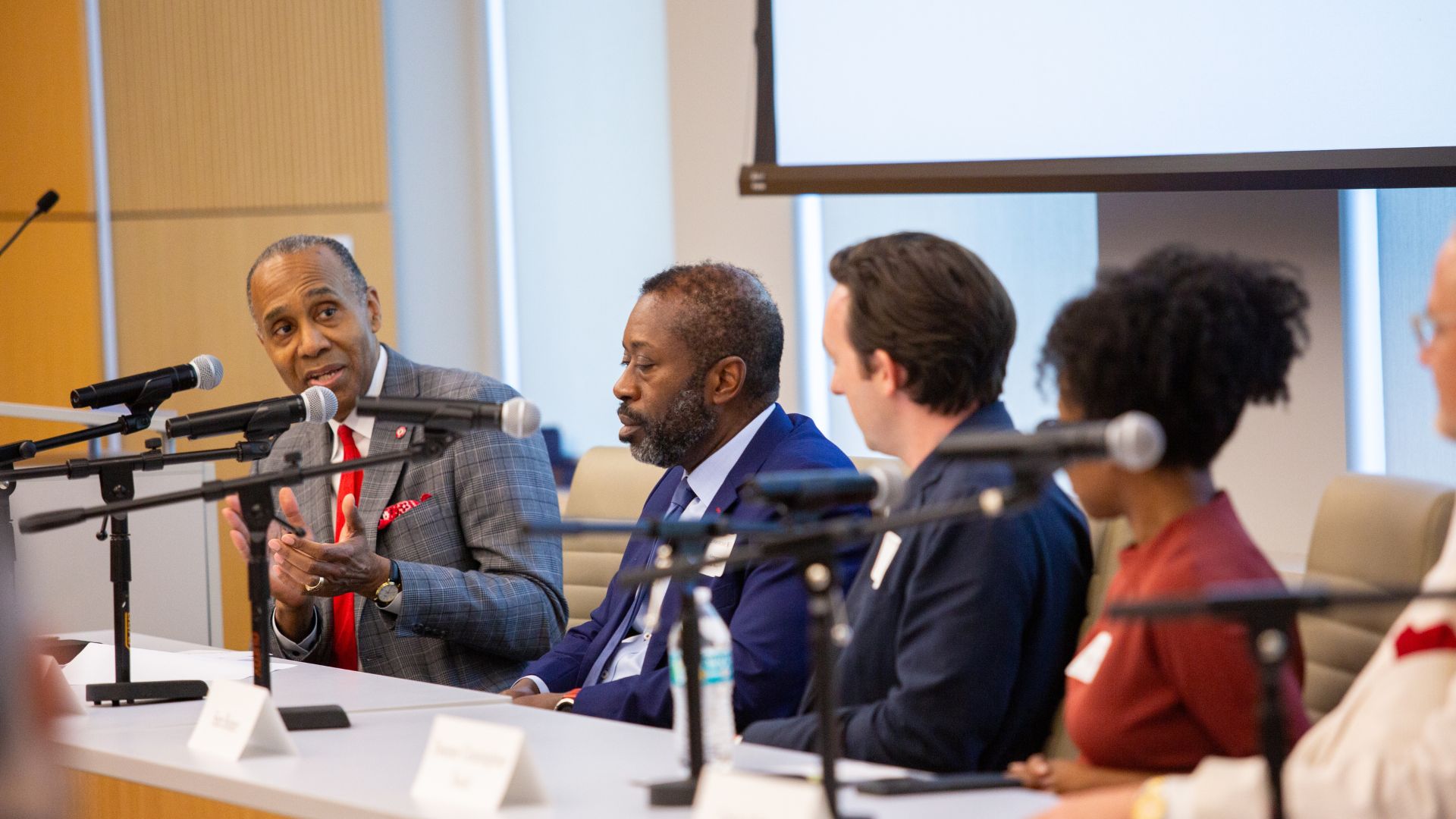 UH Law Dean Leonard M. Baynes speaks into a microphone while moderating a panel of energy executives.