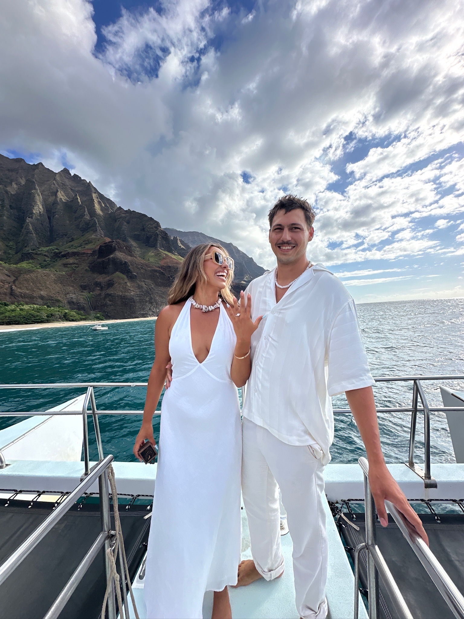Emma Jenny shows her engagement ring while standing with Tanner Shae on a boat in Hawai’i.